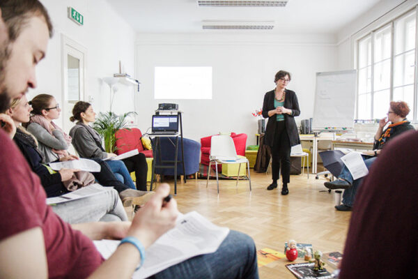 Ein Kurs an der Kinderbüro Academy: die Lehrende spricht zu den Teilnehmenden im Sesselkreis