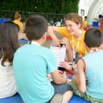 Teammitglied erklärt Kindern anhand einer Kinderuni on Tour-Karte ein Experiment