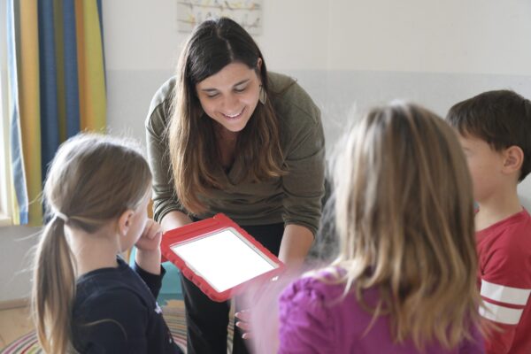 Pädagogin zeigt Kindern das Tablet