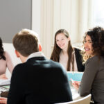 Junge Menschen sitzen am Tisch und diskutieren
