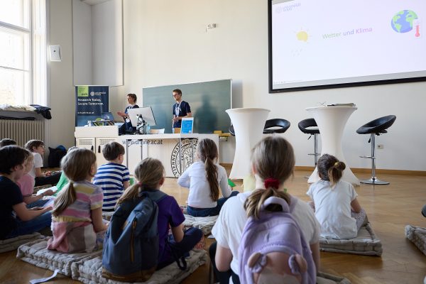 Kinder sitzen am Boden und lauschen gespannt bei der Familienvorlesung über Klimaschutz